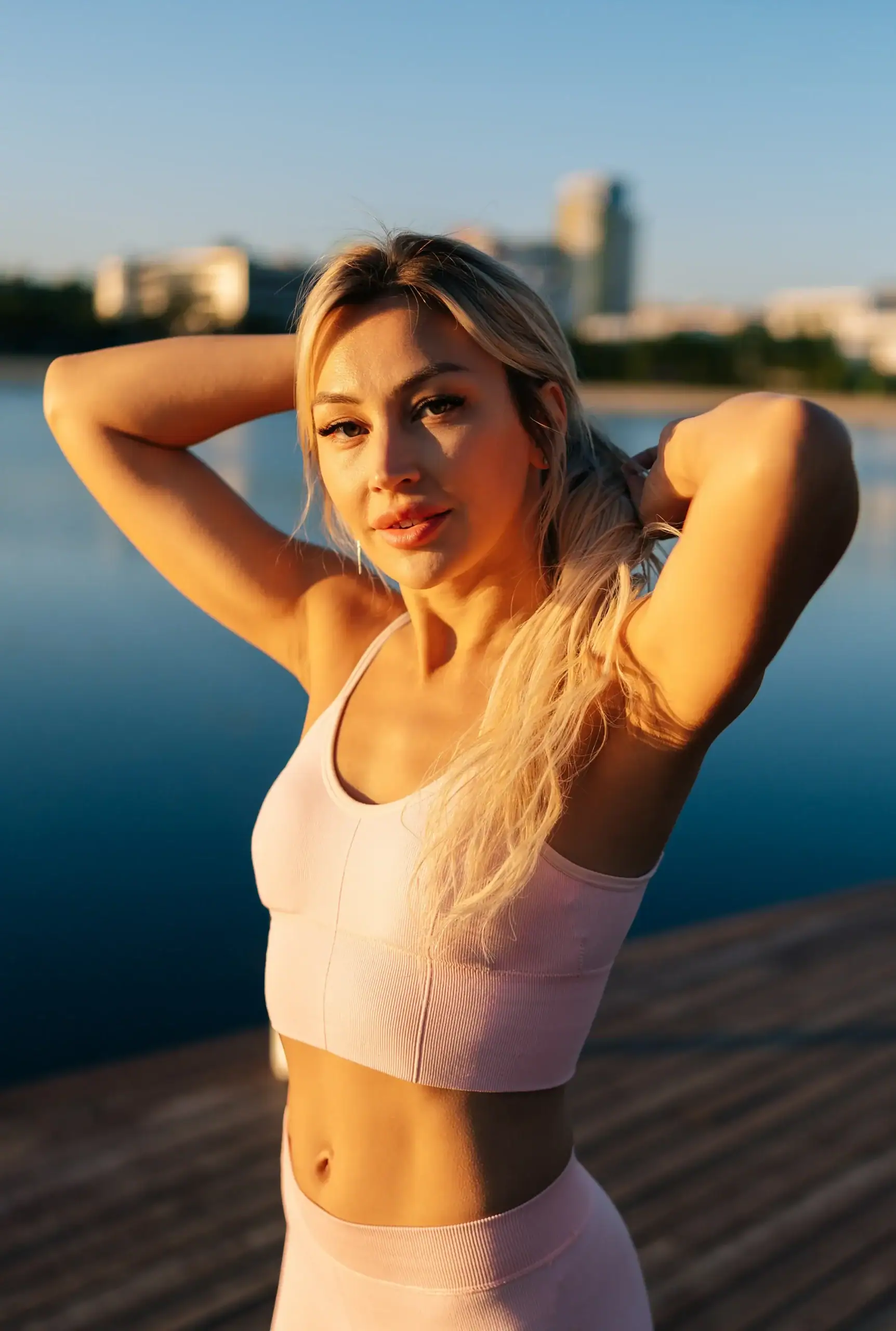 Healthy blond woman in pink workout gear standing by a lake