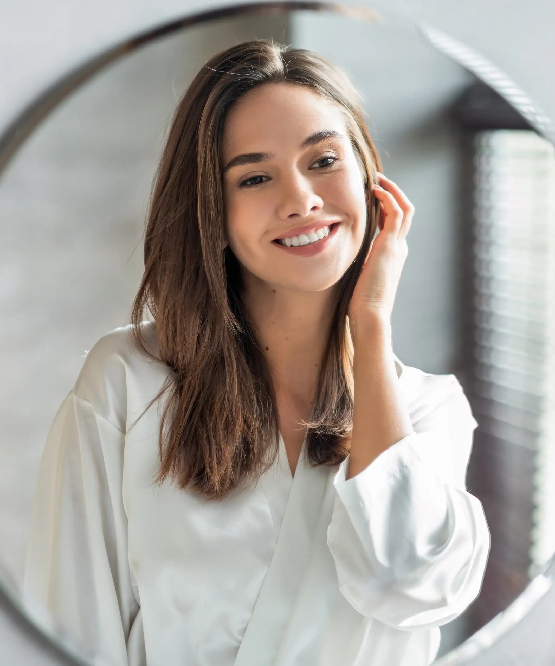 Beautiful woman looks at her reflection in the mirro