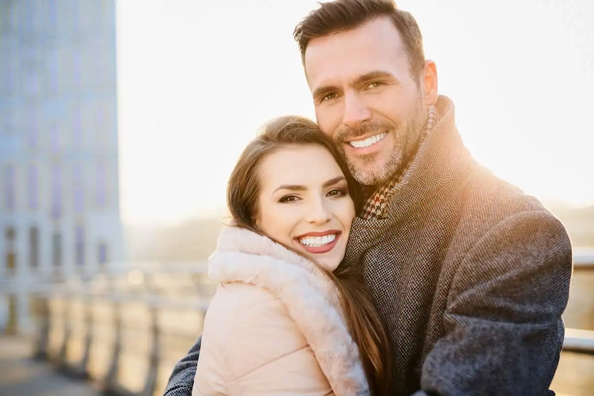 A couple embracing while wearing winter clothing and coats.