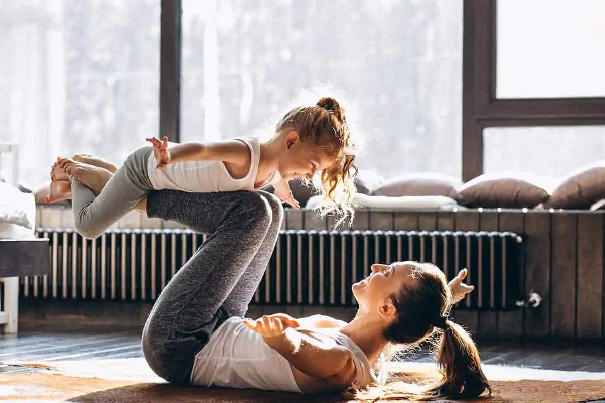 Woman exercising with a toddler girl on her legs