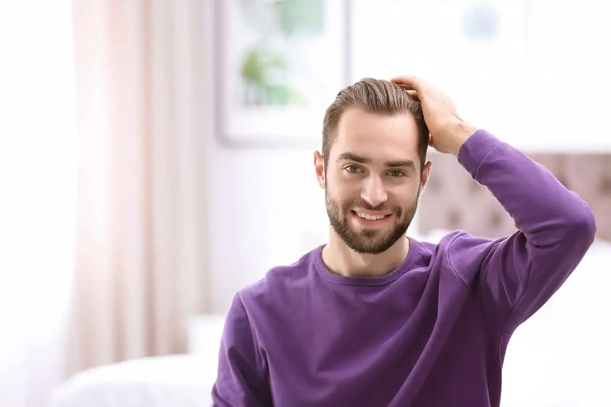 Young man touching the hair on his head.